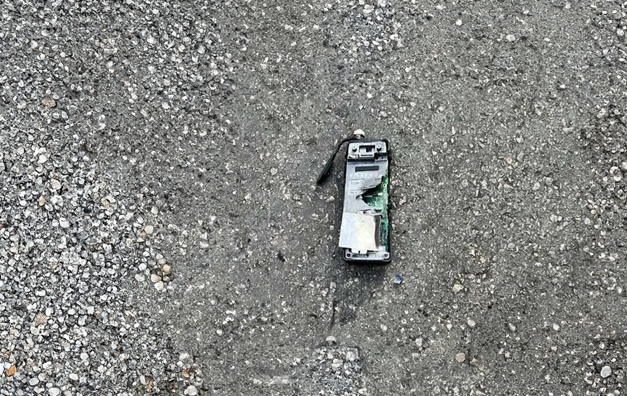 A broken and scorched pager lies on the pavement. It has clearly exploded recently.
